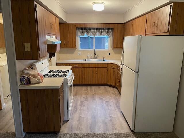 kitchen featuring sink, ornamental molding, light hardwood / wood-style flooring, white appliances, and washer / dryer