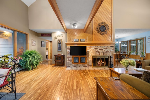 living room with high vaulted ceiling, wooden walls, hardwood / wood-style floors, and a fireplace