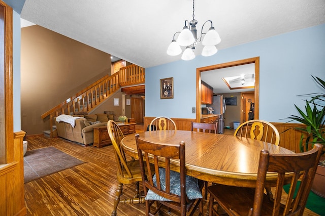 dining space featuring wood walls, wood-type flooring, and an inviting chandelier