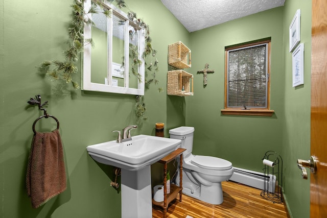 bathroom with toilet, a textured ceiling, hardwood / wood-style flooring, and a baseboard radiator