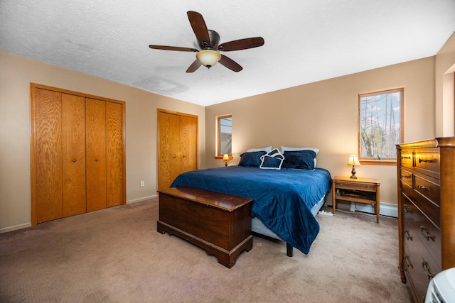 carpeted bedroom with ceiling fan, a textured ceiling, and multiple closets