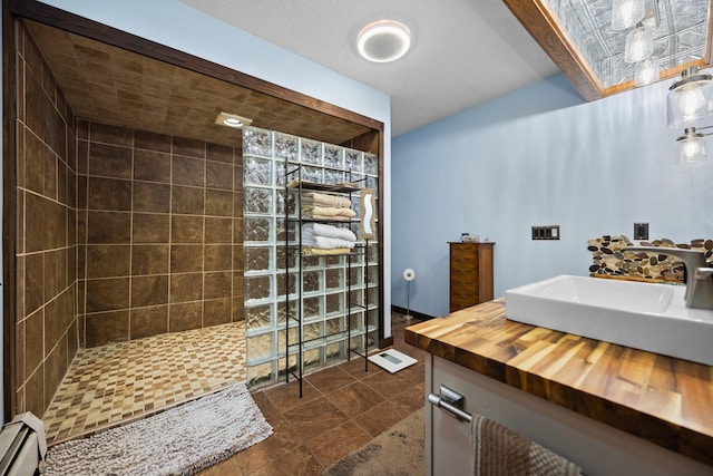 bathroom with baseboard heating, lofted ceiling, sink, and a tile shower