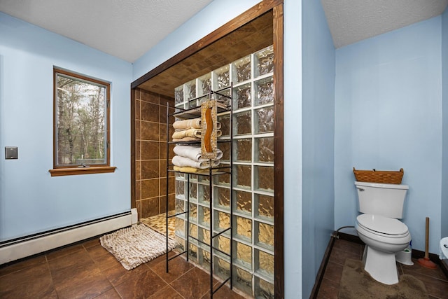 bathroom featuring tile patterned floors, toilet, a textured ceiling, a tile shower, and baseboard heating