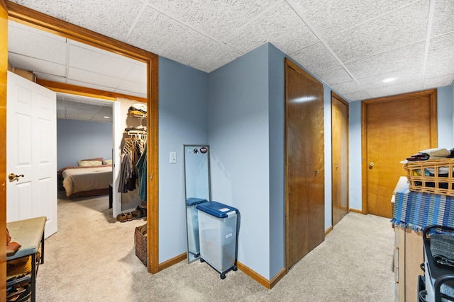 corridor featuring light carpet and a drop ceiling