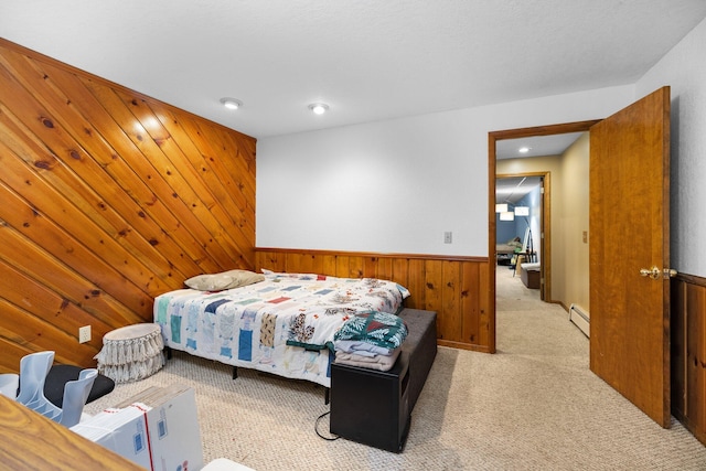 carpeted bedroom with a baseboard heating unit and wooden walls