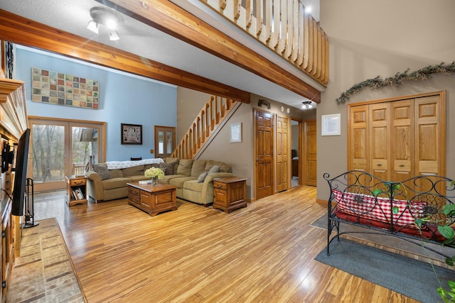 living room featuring a towering ceiling, beam ceiling, and light hardwood / wood-style flooring