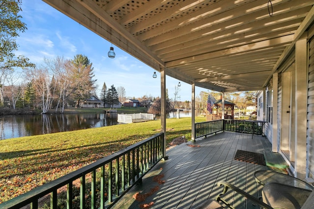 wooden deck with a water view and a lawn