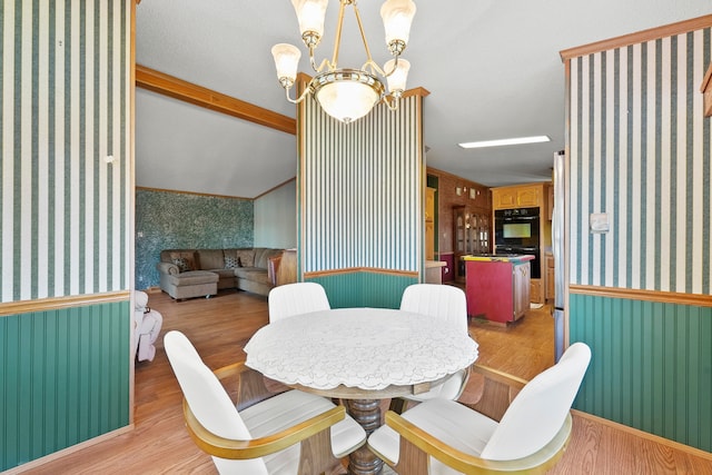 dining area featuring an inviting chandelier, lofted ceiling, ornamental molding, and light hardwood / wood-style flooring