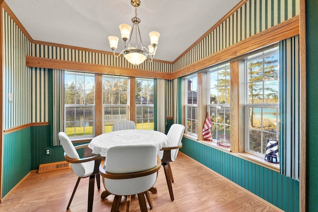 dining area with a chandelier, light wood-type flooring, a textured ceiling, and vaulted ceiling