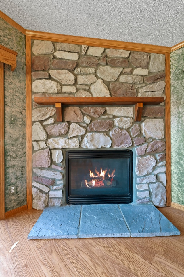 details with a fireplace, ornamental molding, a textured ceiling, and hardwood / wood-style flooring