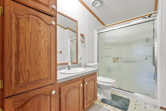 bathroom with crown molding, a textured ceiling, toilet, vanity, and a shower with shower door