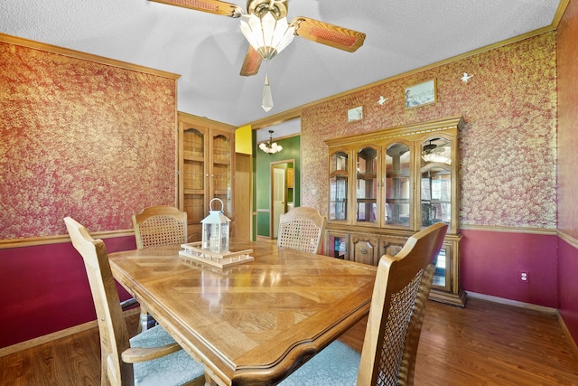 dining room with ceiling fan, dark hardwood / wood-style flooring, a textured ceiling, and ornamental molding