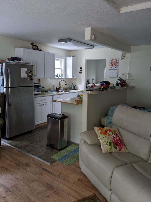 kitchen with sink, stainless steel appliances, hardwood / wood-style floors, a textured ceiling, and white cabinets