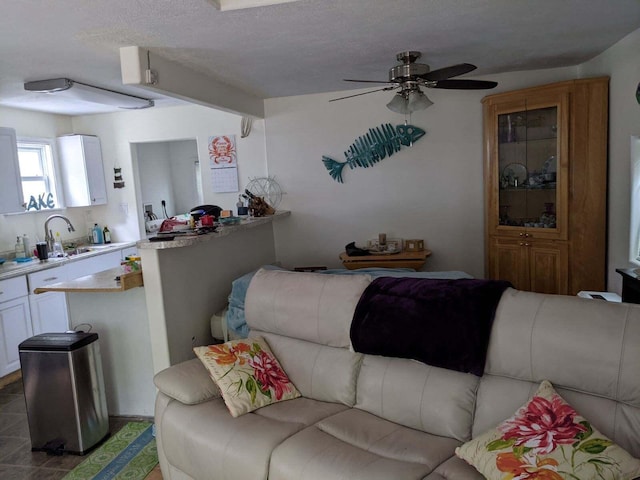 living room featuring sink, ceiling fan, and a textured ceiling