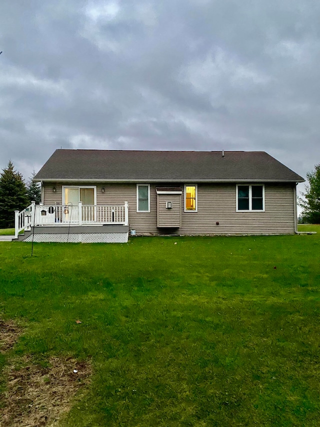 back of house with a deck and a lawn