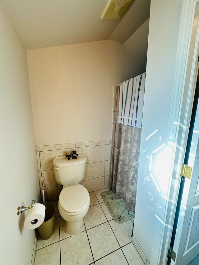 bathroom with walk in shower, tile walls, tile patterned floors, toilet, and vaulted ceiling