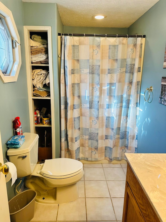 bathroom featuring vanity, tile patterned flooring, toilet, and a textured ceiling