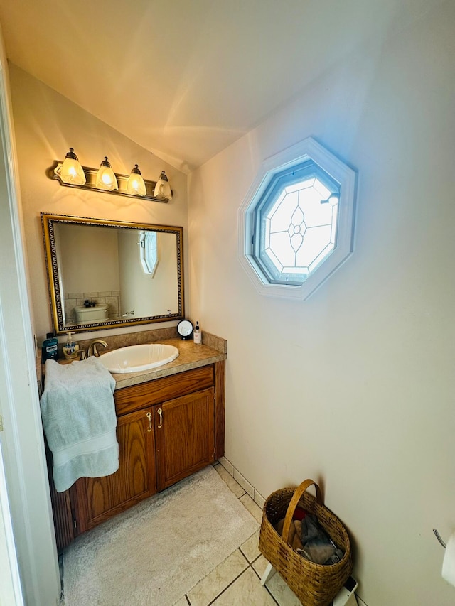 bathroom with tile patterned flooring, vanity, and vaulted ceiling