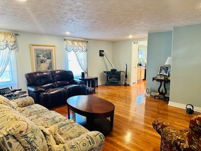 living room featuring hardwood / wood-style floors, a textured ceiling, and a wood stove