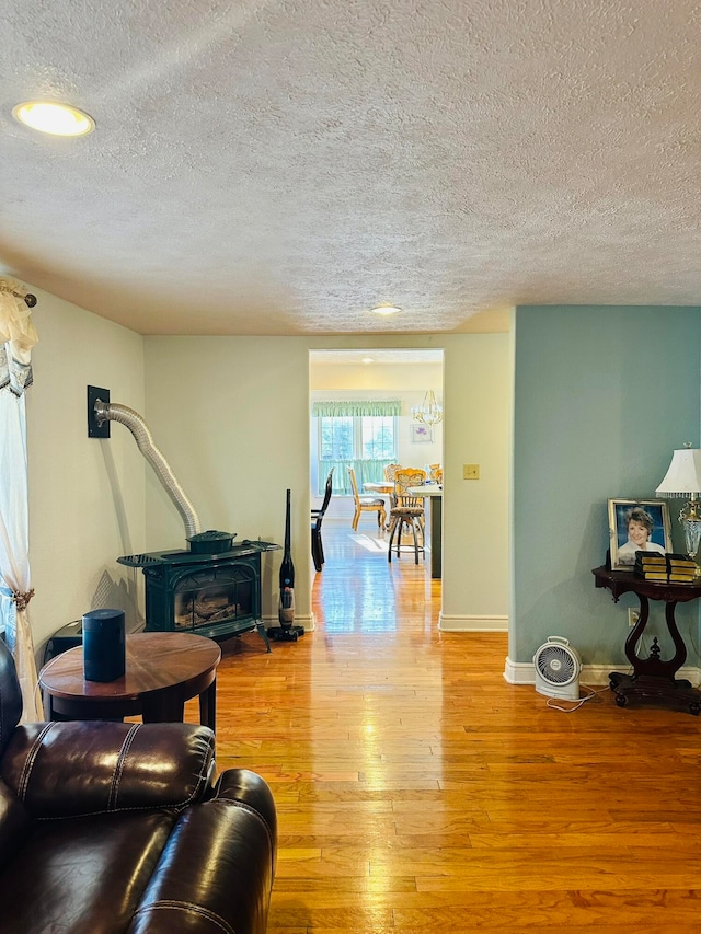 living room featuring light hardwood / wood-style floors, a textured ceiling, and a wood stove