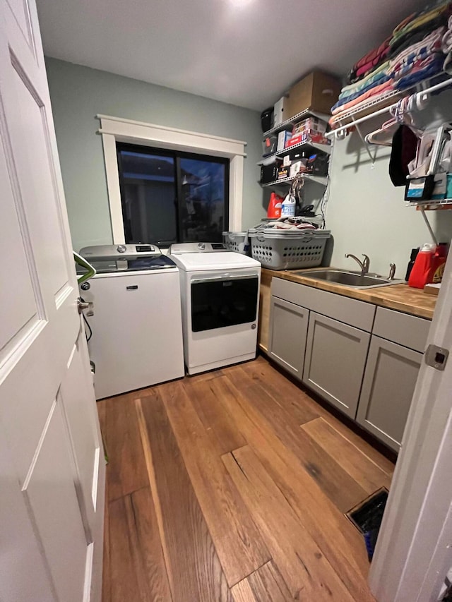 laundry room featuring cabinets, light hardwood / wood-style floors, sink, and washer and dryer