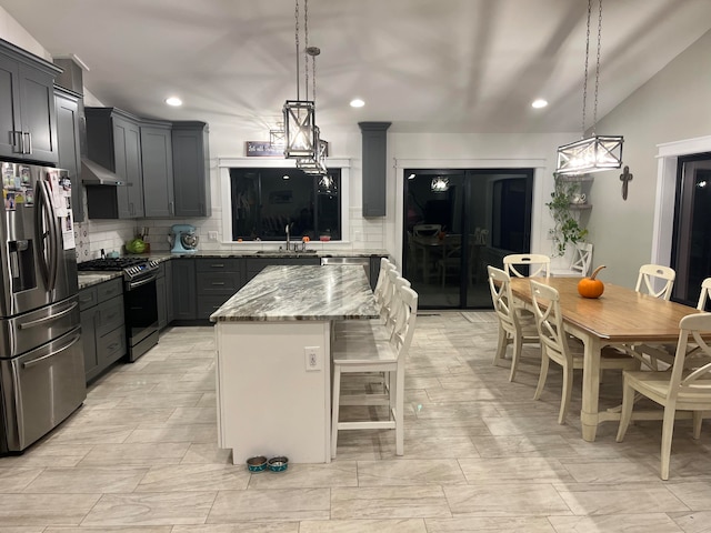 kitchen with appliances with stainless steel finishes, a center island, backsplash, and decorative light fixtures