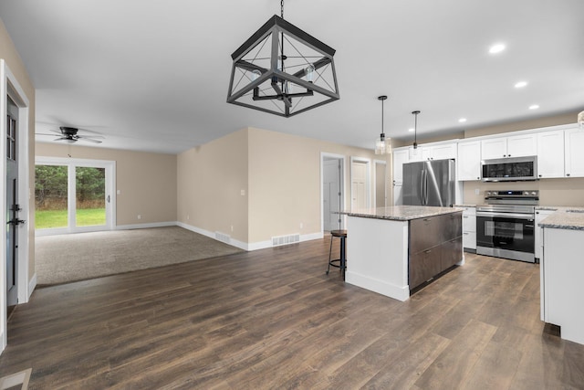 kitchen with white cabinetry, ceiling fan, stainless steel appliances, decorative light fixtures, and a kitchen island