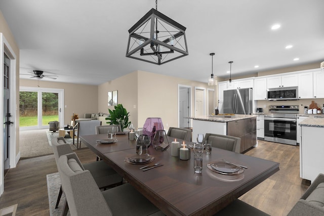 dining room with dark hardwood / wood-style flooring and ceiling fan with notable chandelier