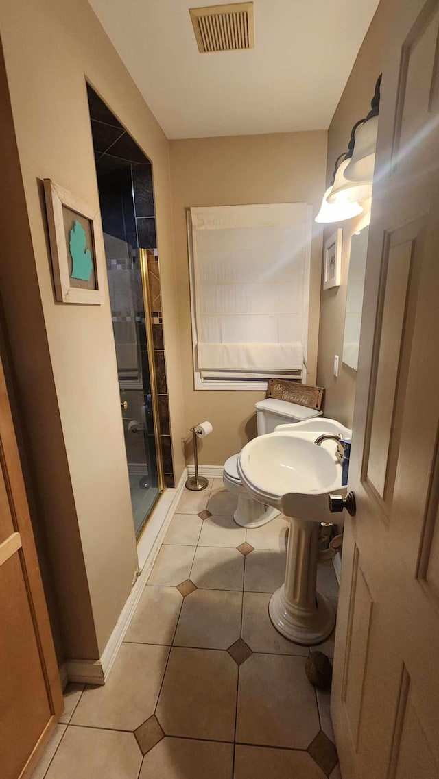 bathroom with toilet, tile patterned floors, an enclosed shower, and sink