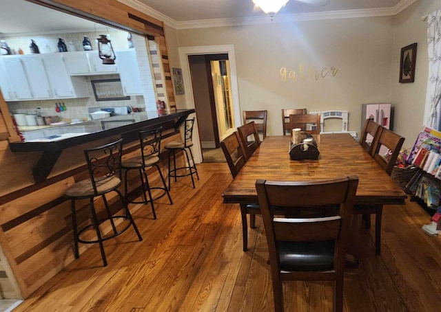 dining space with wood-type flooring and crown molding