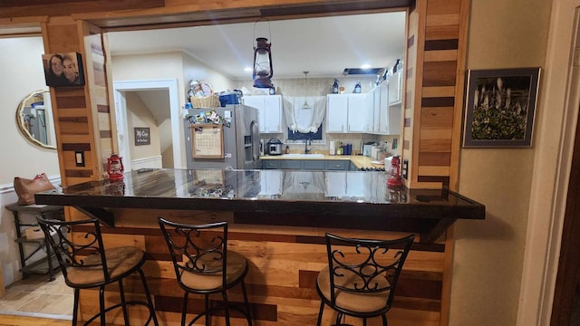 bar featuring light hardwood / wood-style flooring, stainless steel refrigerator with ice dispenser, and white cabinets