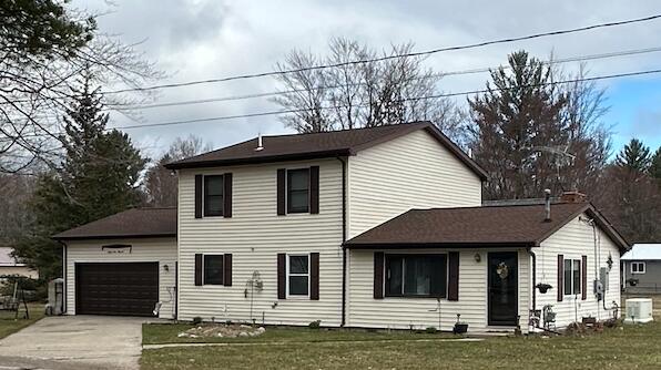 view of front of house featuring cooling unit, a front yard, and a garage