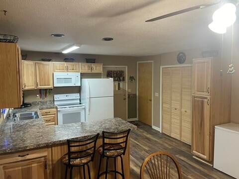 kitchen featuring sink, dark hardwood / wood-style flooring, white appliances, and kitchen peninsula