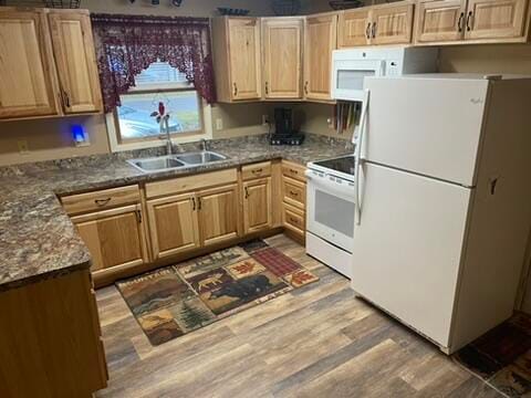 kitchen with dark stone counters, sink, hardwood / wood-style floors, and white appliances