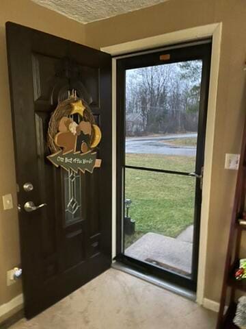 doorway to outside with a water view and a textured ceiling