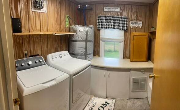 laundry room featuring wooden walls and washer and dryer