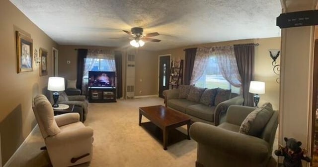 living room featuring ceiling fan, light carpet, and a textured ceiling