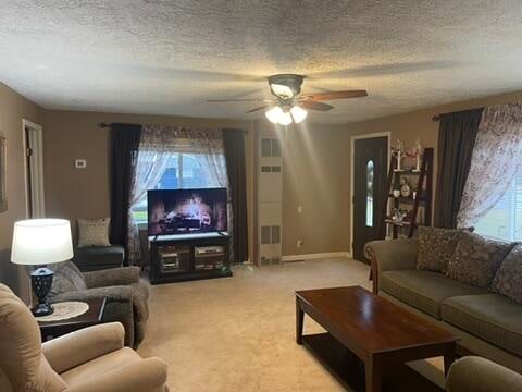 living room featuring a textured ceiling, light colored carpet, plenty of natural light, and ceiling fan