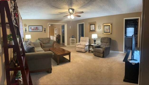 carpeted living room featuring a textured ceiling and ceiling fan