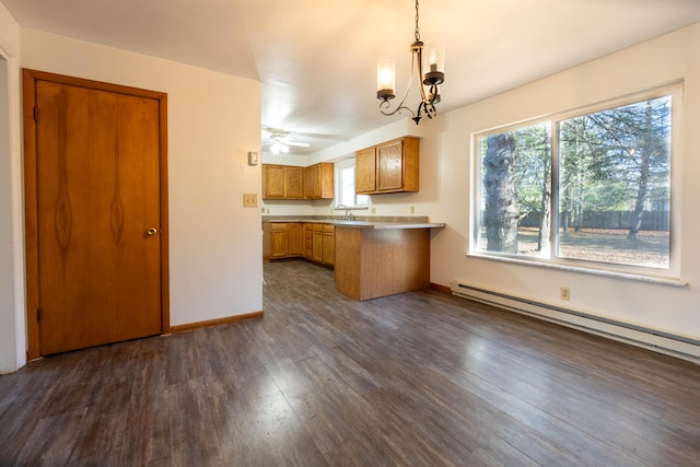 kitchen featuring sink, dark wood-type flooring, a baseboard radiator, kitchen peninsula, and pendant lighting