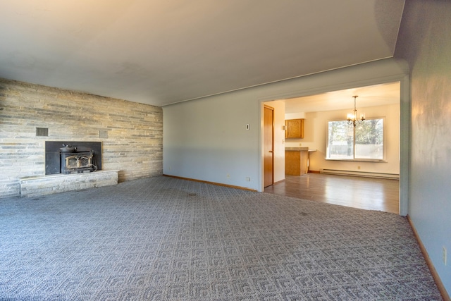 unfurnished living room with a notable chandelier, a wood stove, and baseboard heating