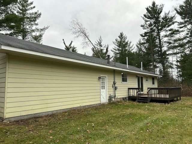 back of house featuring a lawn and a wooden deck