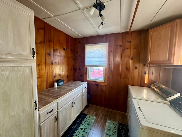 clothes washing area with cabinets, dark hardwood / wood-style floors, wooden walls, and washing machine and clothes dryer