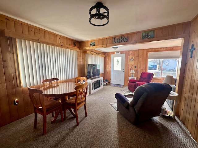 carpeted dining area featuring wooden walls