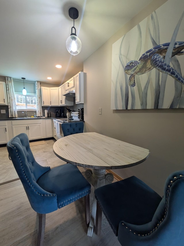 dining space featuring sink, light hardwood / wood-style floors, and lofted ceiling