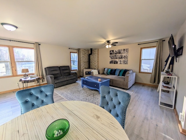 living room featuring light hardwood / wood-style flooring, a wood stove, and ceiling fan