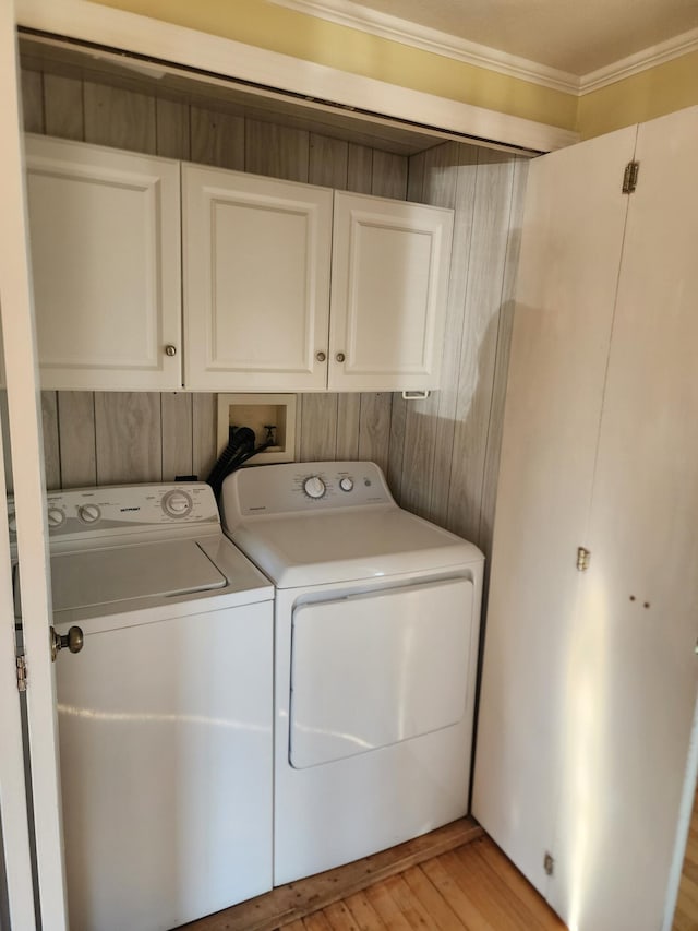 washroom with cabinets, ornamental molding, washing machine and dryer, light hardwood / wood-style floors, and wood walls