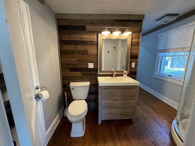 bathroom with wood-type flooring, vanity, toilet, and wood walls