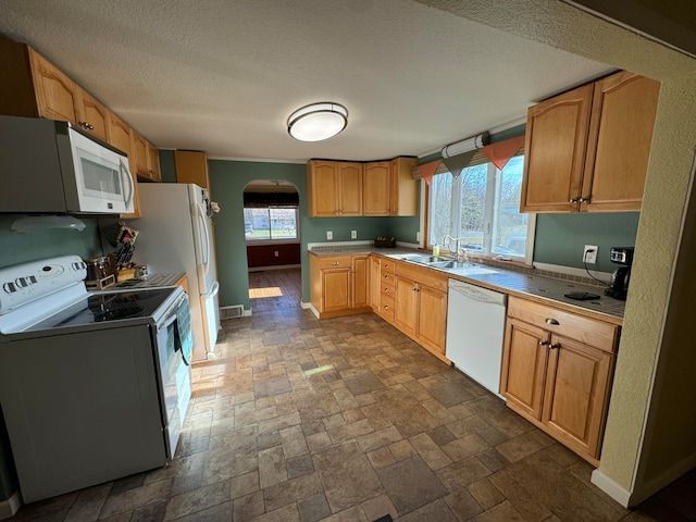 kitchen with a textured ceiling, white appliances, and sink