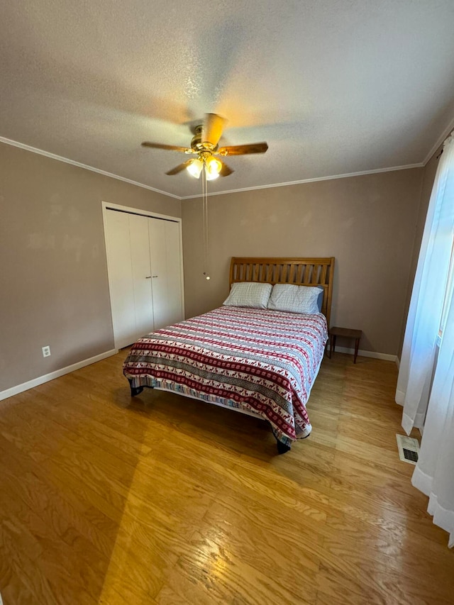 bedroom featuring hardwood / wood-style flooring, ceiling fan, ornamental molding, a textured ceiling, and a closet